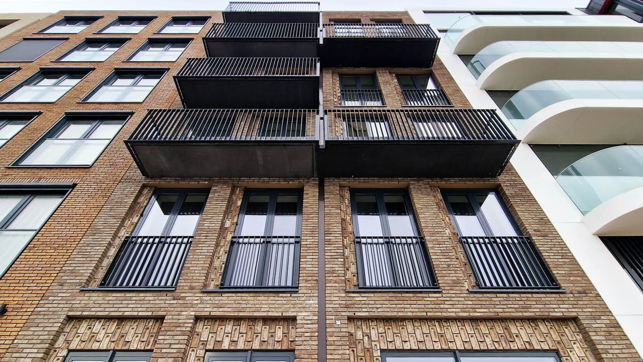 Gevel van Appartementengebouw 10-13: gele baksteen met metselwerkdetails, stalen balkons en Franse balkons